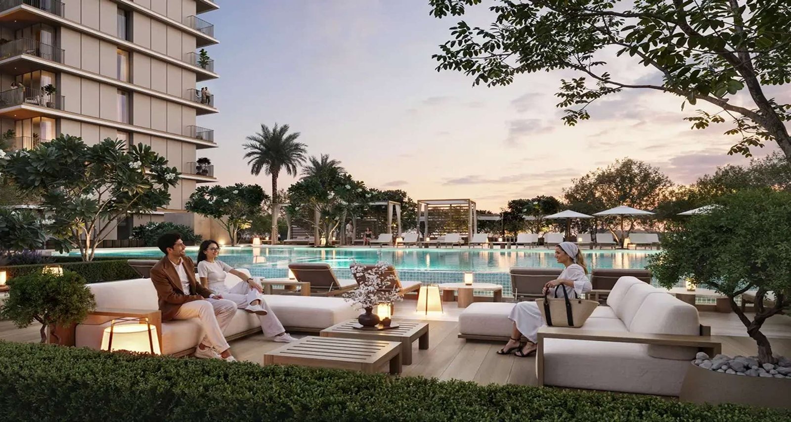 Pool deck at Dubai Creek Gardens at dusk — residents on outdoor lounge seating beside the pool, framed by mature trees and planting below the residences